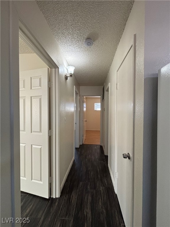 corridor featuring a textured ceiling and dark hardwood / wood-style floors