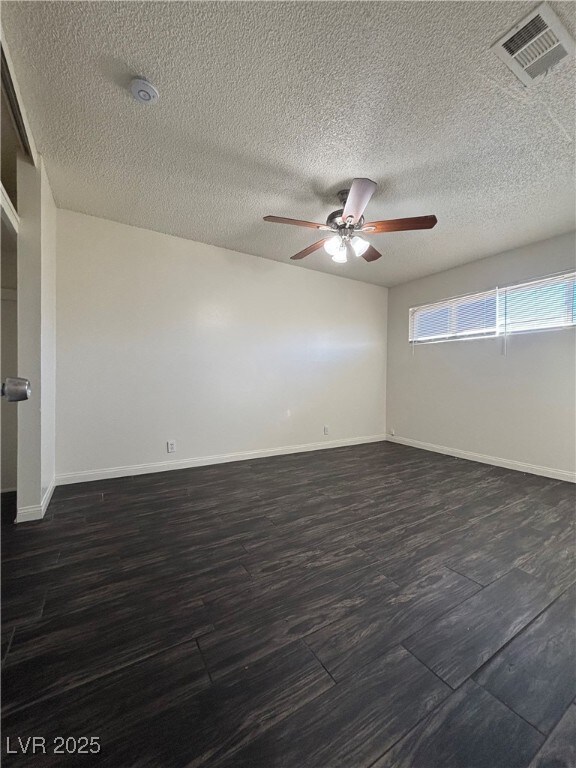 spare room featuring a textured ceiling, ceiling fan, and dark wood-type flooring