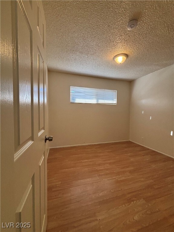 spare room featuring wood-type flooring, a textured ceiling, and a wealth of natural light