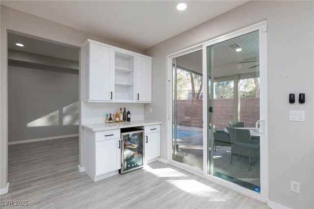 bar featuring white cabinetry, light wood-type flooring, and wine cooler