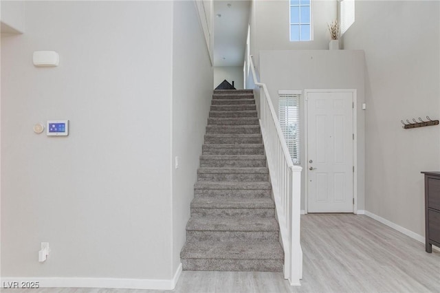 stairway with a high ceiling and wood-type flooring