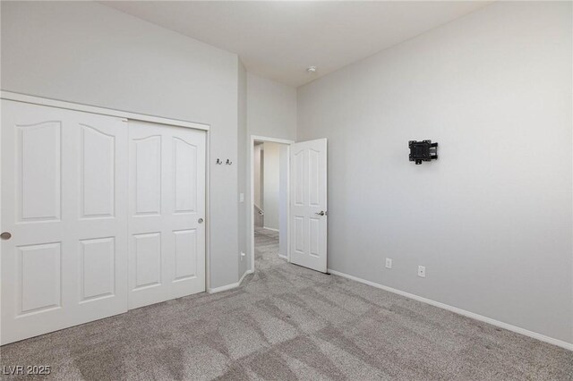 unfurnished bedroom with a towering ceiling, a closet, and light carpet