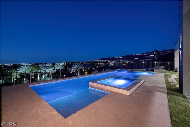 pool at twilight featuring a patio and an in ground hot tub