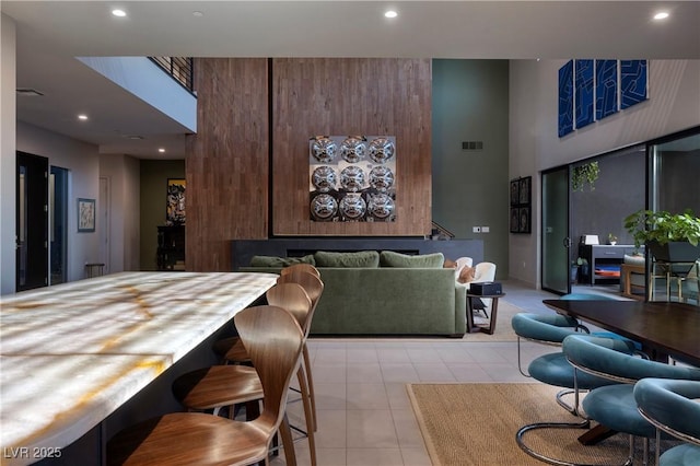 dining area with a towering ceiling and light tile patterned floors