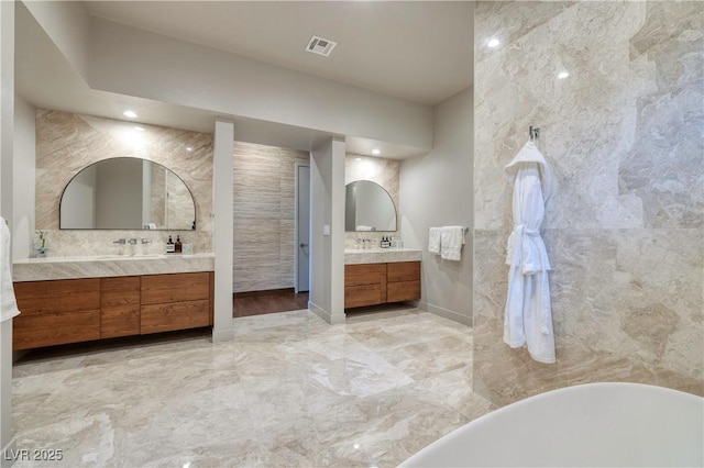 bathroom with a bath, decorative backsplash, and vanity