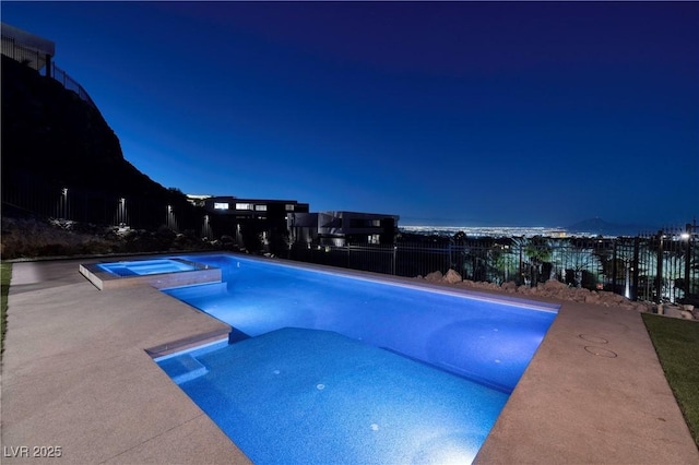 pool at twilight featuring an in ground hot tub