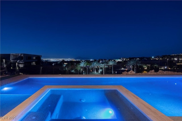 pool at twilight featuring an in ground hot tub