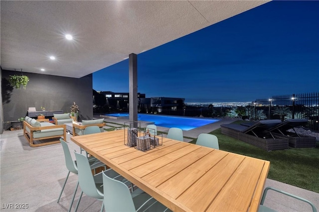 patio at night with a fenced in pool and an outdoor living space