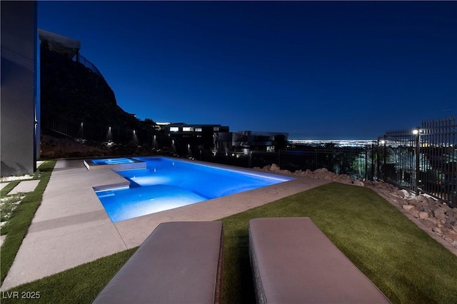 pool at twilight with a patio area, a yard, and an in ground hot tub