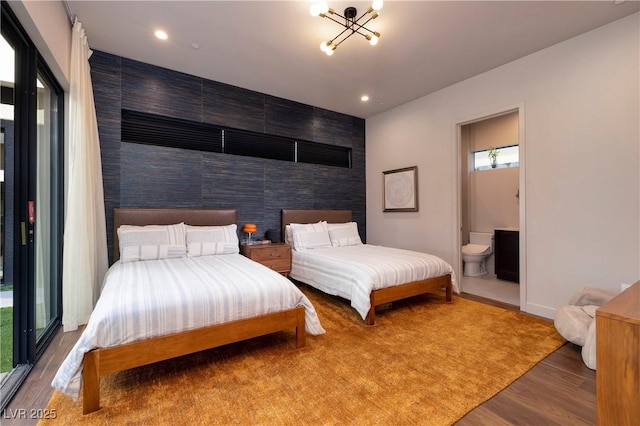 bedroom featuring ensuite bathroom, an inviting chandelier, and wood-type flooring