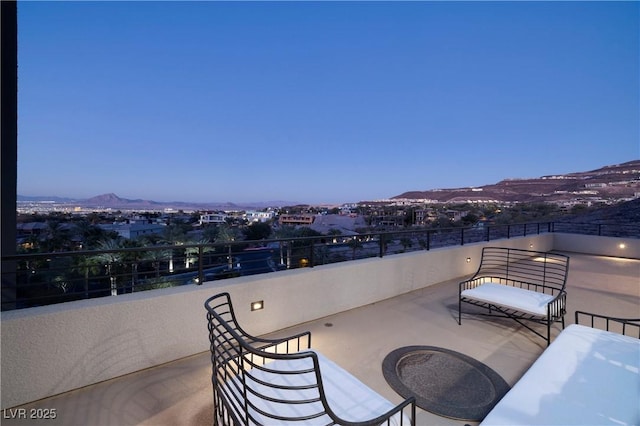 patio terrace at dusk featuring a balcony and a mountain view