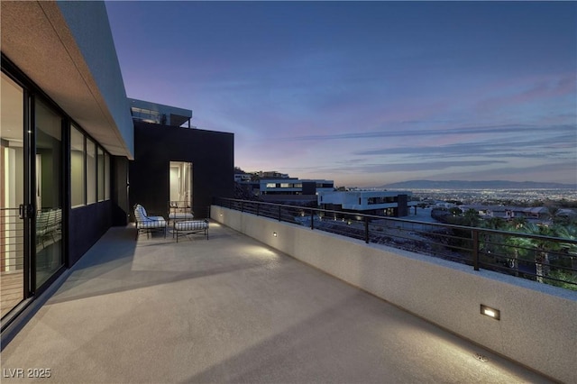 patio terrace at dusk featuring a balcony