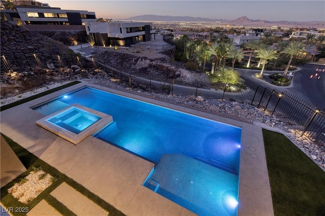 pool at dusk with an in ground hot tub and a mountain view