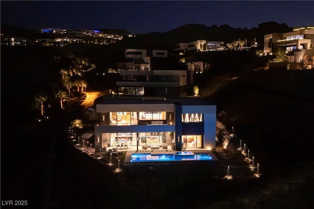 back house at twilight with a patio area and a balcony