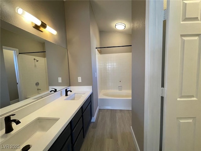 bathroom featuring wood-type flooring, vanity, and tiled shower / bath