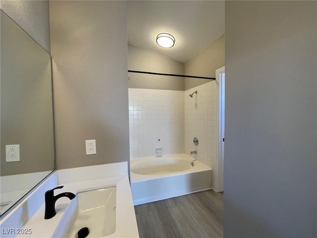 bathroom featuring lofted ceiling, tiled shower / bath combo, and wood-type flooring