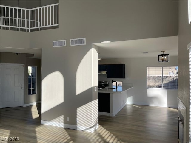 interior space featuring sink, a towering ceiling, an inviting chandelier, and dark hardwood / wood-style floors