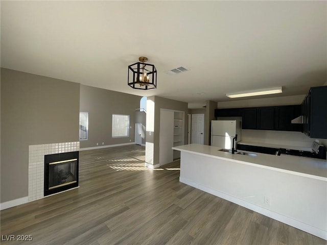 kitchen with sink, a tile fireplace, white fridge, stove, and dark wood-type flooring