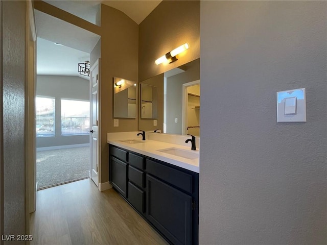 bathroom featuring vaulted ceiling, wood-type flooring, and vanity