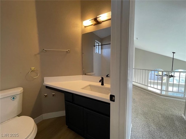 bathroom featuring toilet, vanity, a chandelier, and lofted ceiling