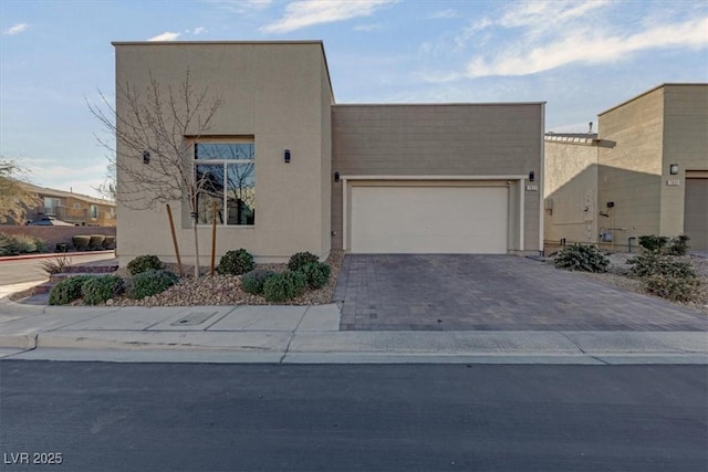 view of front of home with a garage, decorative driveway, and stucco siding