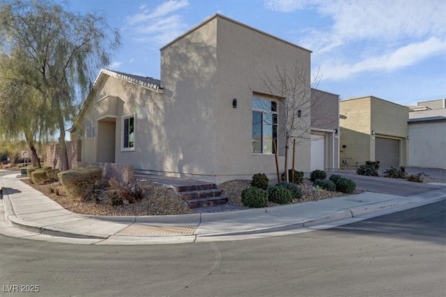 view of front facade featuring driveway, an attached garage, and stucco siding