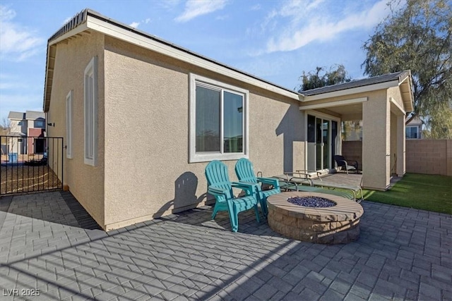 back of house with a patio area, a fire pit, and stucco siding