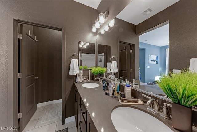 full bath with a textured wall, visible vents, a sink, and double vanity