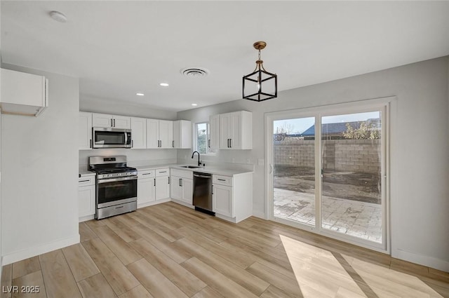 kitchen featuring white cabinets, appliances with stainless steel finishes, and hanging light fixtures