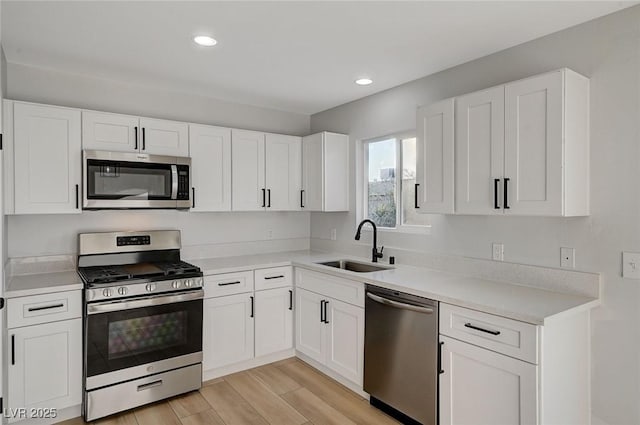 kitchen featuring appliances with stainless steel finishes, light hardwood / wood-style flooring, white cabinets, and sink