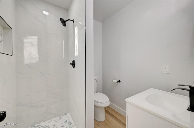 bathroom featuring tiled shower, hardwood / wood-style floors, vanity, and toilet