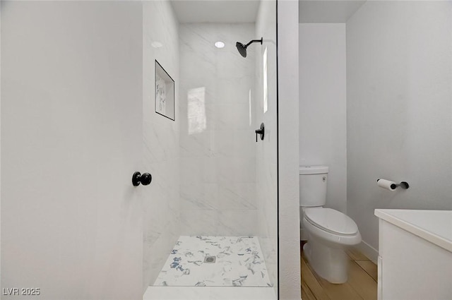 bathroom featuring a tile shower and toilet