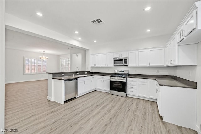 kitchen featuring kitchen peninsula, decorative light fixtures, light hardwood / wood-style floors, white cabinets, and appliances with stainless steel finishes