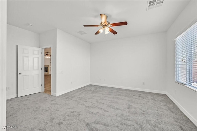 unfurnished room with ceiling fan, light colored carpet, and a wealth of natural light