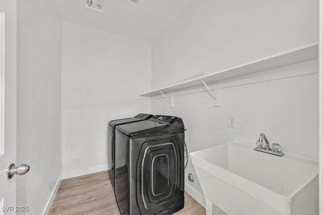 laundry room featuring sink, separate washer and dryer, and light hardwood / wood-style flooring