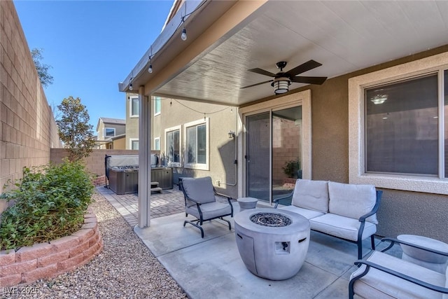 view of patio with ceiling fan, an outdoor fire pit, and a hot tub