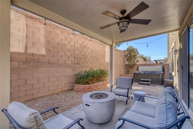 view of patio / terrace featuring ceiling fan, a hot tub, and a fire pit