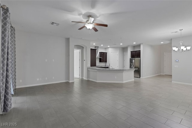 unfurnished living room featuring ceiling fan with notable chandelier