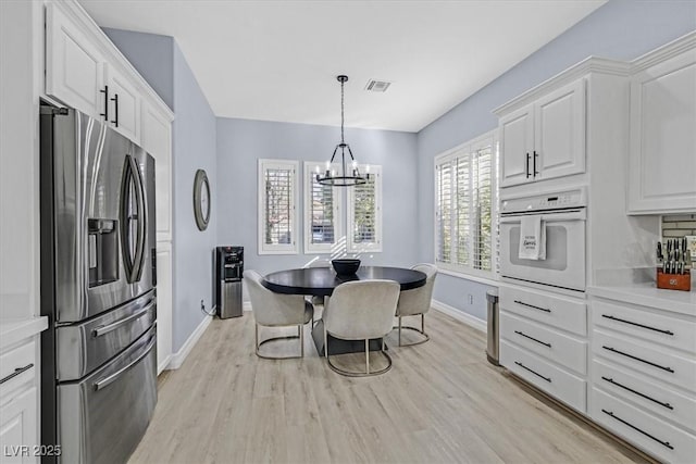 kitchen with a chandelier, decorative light fixtures, stainless steel fridge with ice dispenser, oven, and white cabinets