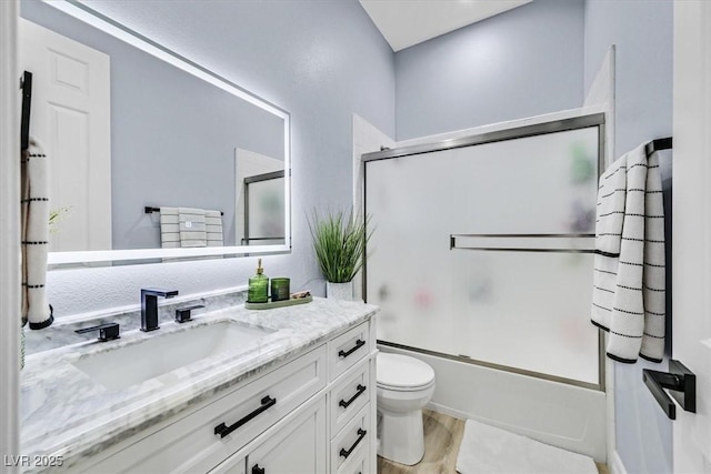 full bathroom with vanity, shower / bath combination with glass door, toilet, and hardwood / wood-style flooring