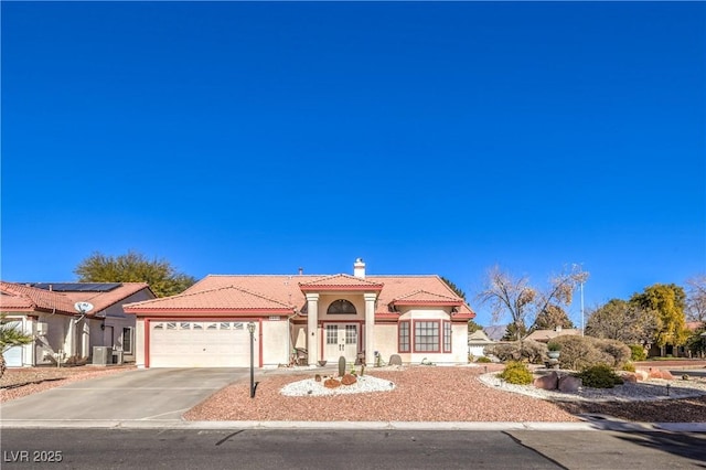 mediterranean / spanish-style house with central air condition unit and a garage