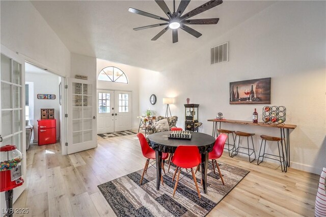 dining space with high vaulted ceiling, ceiling fan, french doors, and light hardwood / wood-style flooring