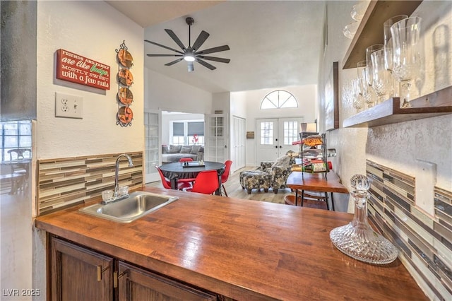 kitchen featuring vaulted ceiling, ceiling fan, french doors, decorative backsplash, and sink