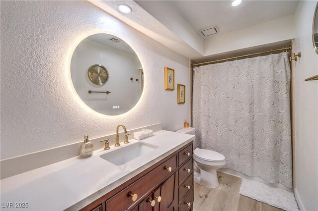 bathroom with toilet, vanity, and wood-type flooring