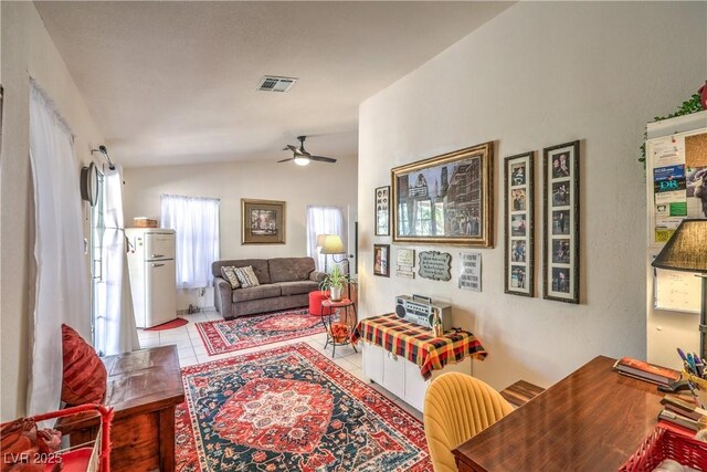 tiled living room with ceiling fan and vaulted ceiling