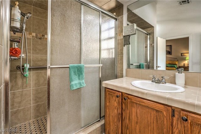 bathroom with a shower with shower door and vanity