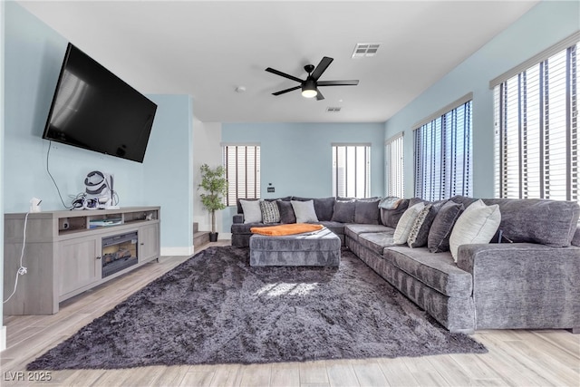 living room with ceiling fan, light wood-type flooring, and plenty of natural light