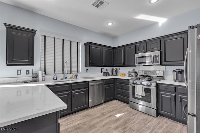 kitchen with stainless steel appliances, sink, and light hardwood / wood-style floors