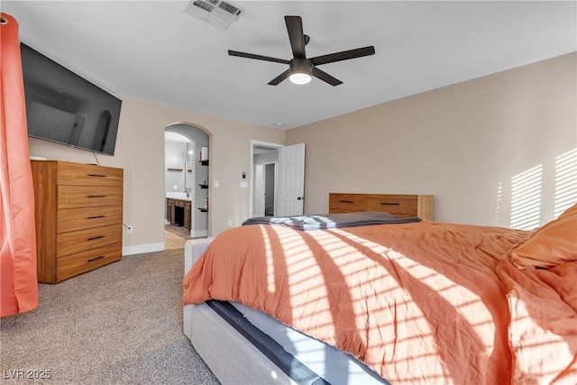 bedroom with ceiling fan, light colored carpet, and ensuite bathroom