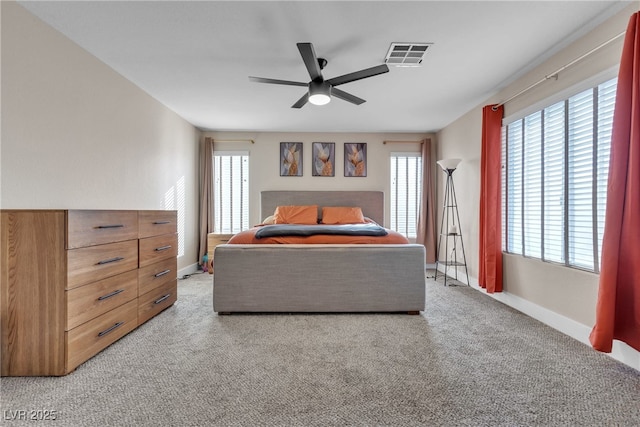 bedroom featuring ceiling fan, light colored carpet, and multiple windows